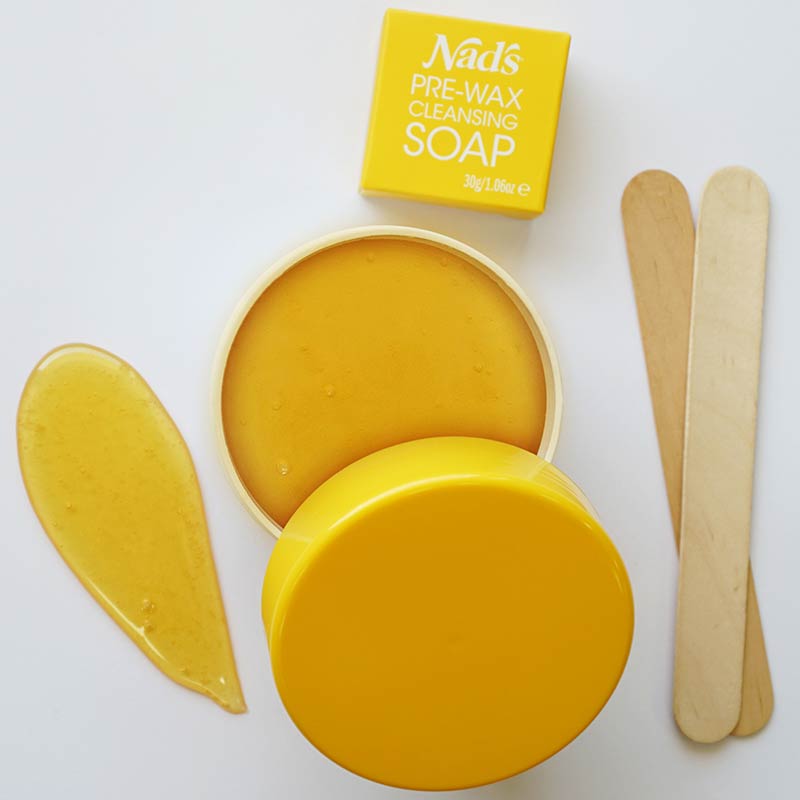 Nad's Natural Sugar Wax | Your new beauty product secret Nad's Natural Sugar Wax open container, smear of wax, pre-wax cleansing soap, and wooden applicators